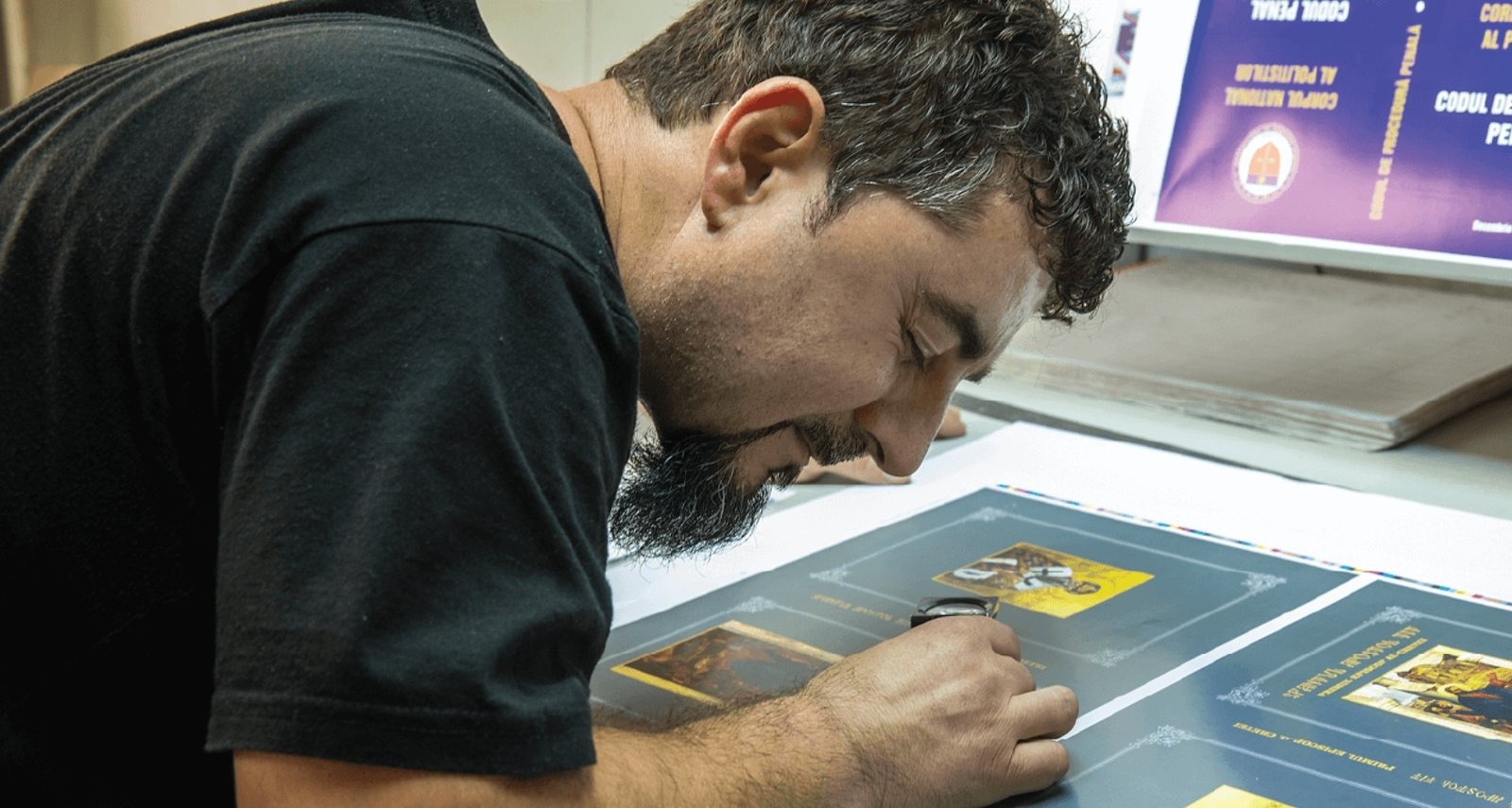 Tipograf verificând cu lupa o coală tipărită, în hala Grafoanaytis